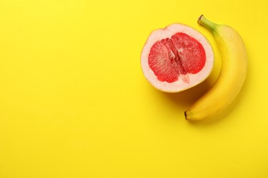 Photo of Banana and half of grapefruit on yellow background, flat lay with space for text. Sex concept