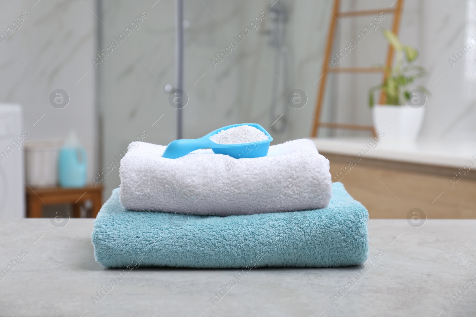 Photo of Clean towels and detergent on table indoors