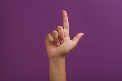 Photo of Teenage boy pointing at something on purple background, closeup
