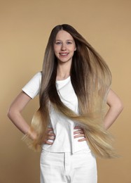 Photo of Teenage girl with strong healthy hair on beige background