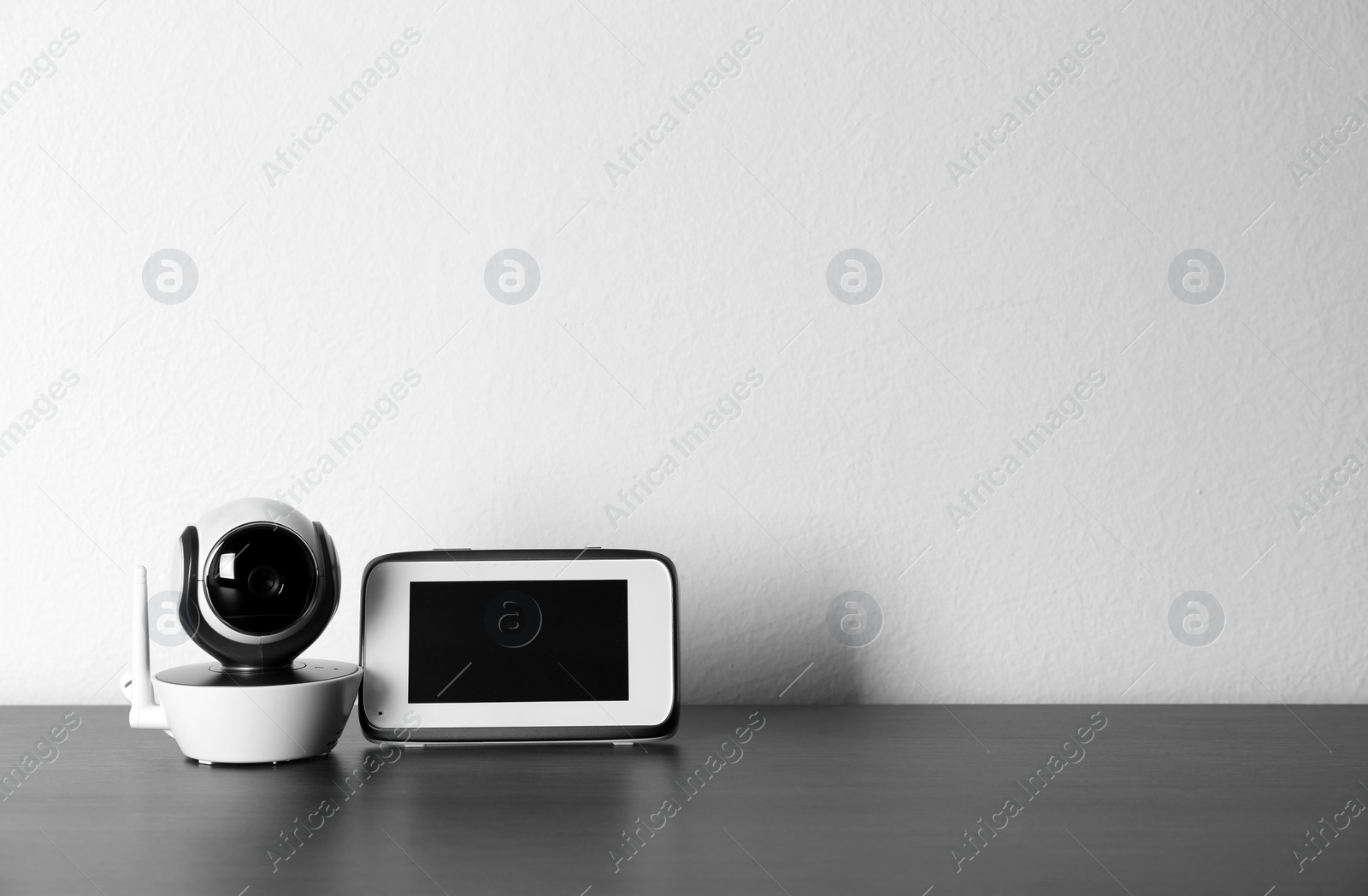 Photo of Baby monitors on wooden table, space for text. CCTV equipment