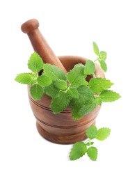 Photo of Wooden mortar with pestle and fresh green lemon balm leaves isolated on white