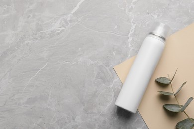 Photo of Dry shampoo spray and eucalyptus on light grey marble table, flat lay. Space for text