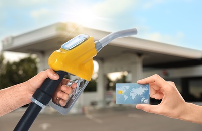 Image of Man holding credit card and worker with fuel nozzle at gas station, closeup. Cashless payment