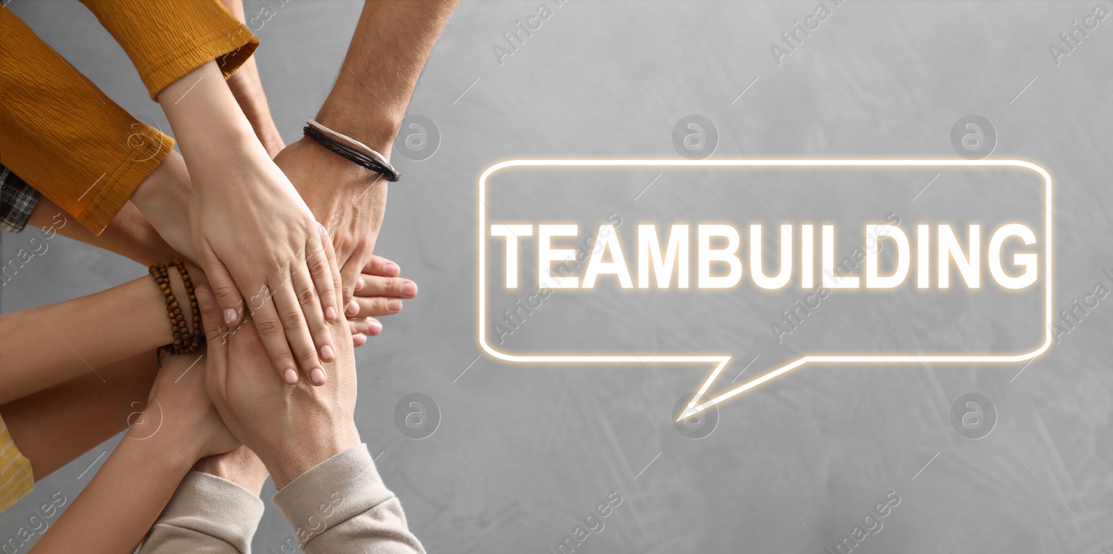 Image of People holding hands together over grey stone background, closeup. Teambuilding concept