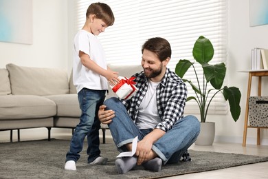 Photo of Happy Father's Day. Son giving gift box to his father with greeting card at home