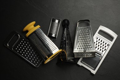 Photo of Different modern graters on black table, flat lay