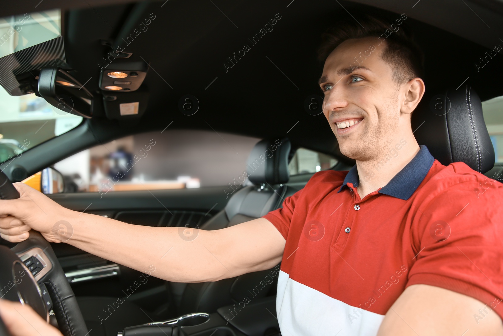 Photo of Young man sitting in driver's seat of auto. Buying new car