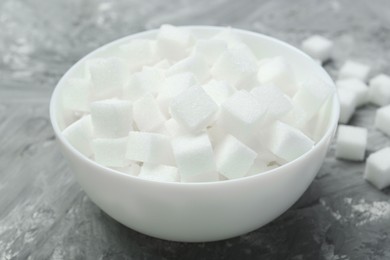 Photo of White sugar cubes in bowl on grey table