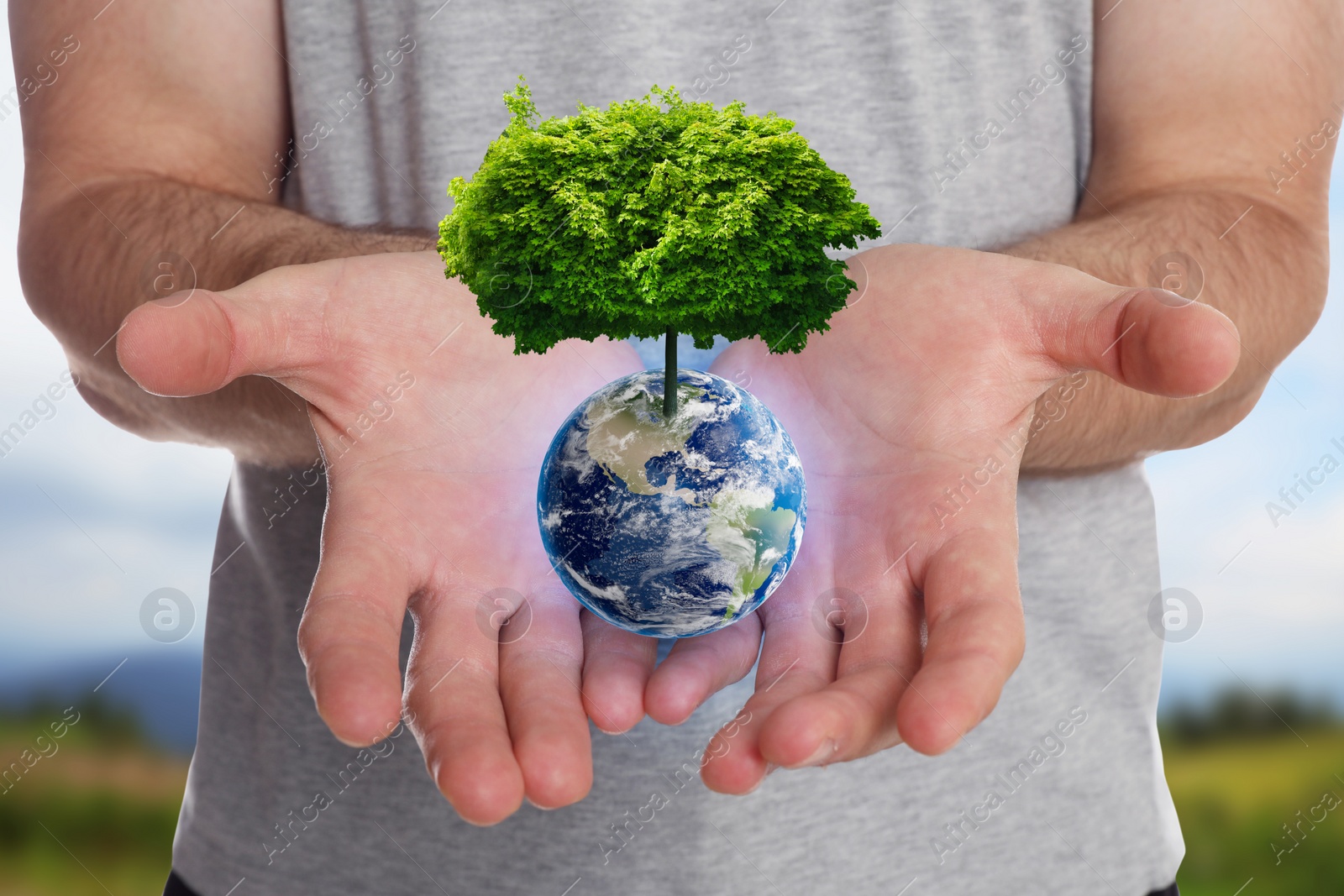 Image of Make Earth green. Man holding globe with tree on top outdoors, closeup