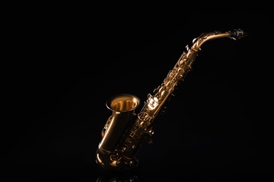 Photo of Beautiful saxophone on black background. Musical instrument