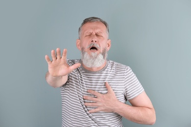 Photo of Mature man having heart attack on color background