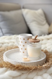 Photo of Cup of drink and candles on knitted plaid in room. Interior elements