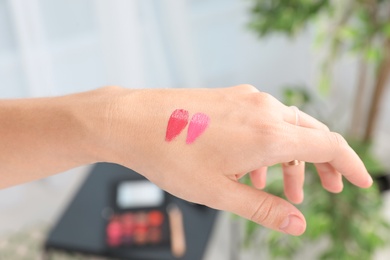 Woman testing and choosing lip gloss color on hand, closeup