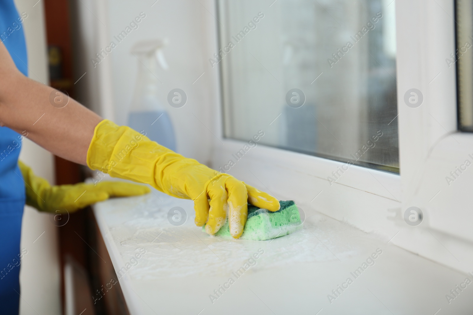 Photo of Woman cleaning window sill with sponge, closeup