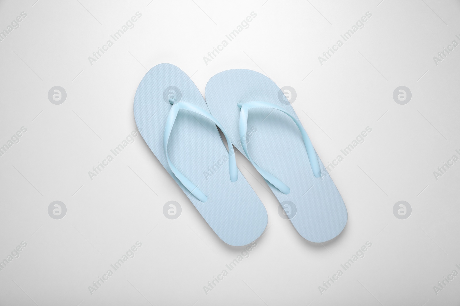 Photo of Light blue flip flops on white background, top view