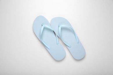 Photo of Light blue flip flops on white background, top view
