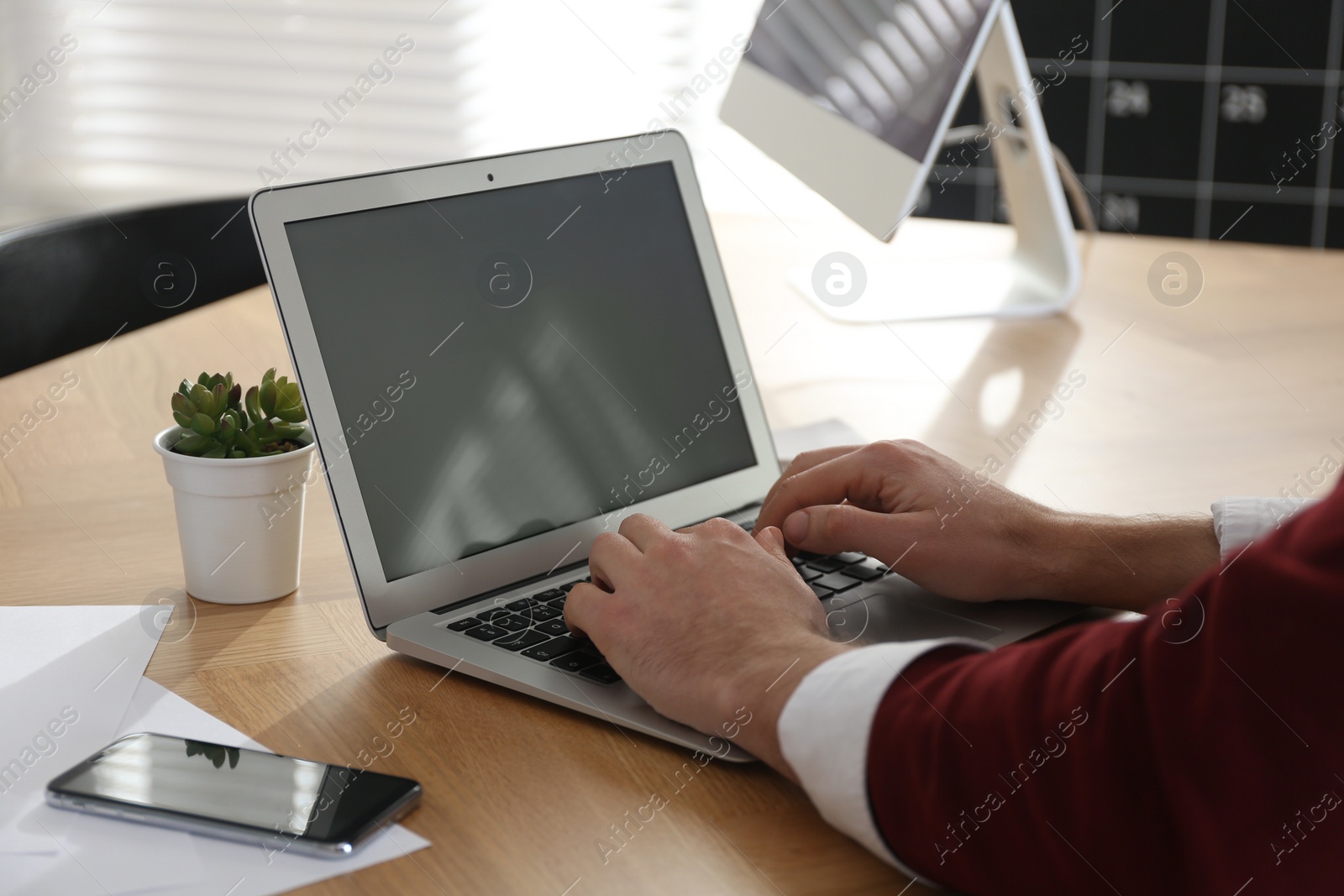 Photo of Freelancer working on laptop at table indoors, closeup