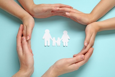 Photo of People with paper family cutout on light blue background, top view