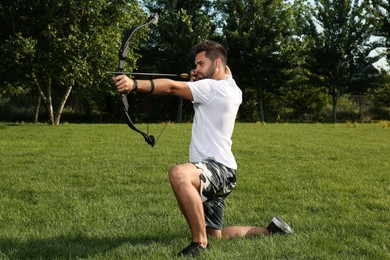 Photo of Man with bow and arrow practicing archery in park
