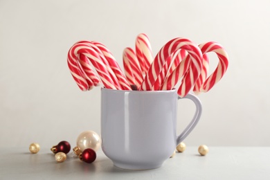 Photo of Candy canes and Christmas balls on light grey table