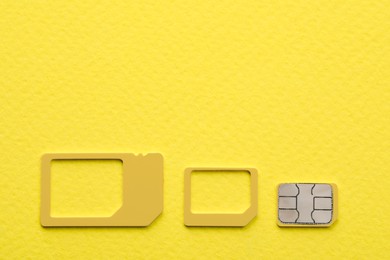 Multi SIM card on yellow background, flat lay. Space for text