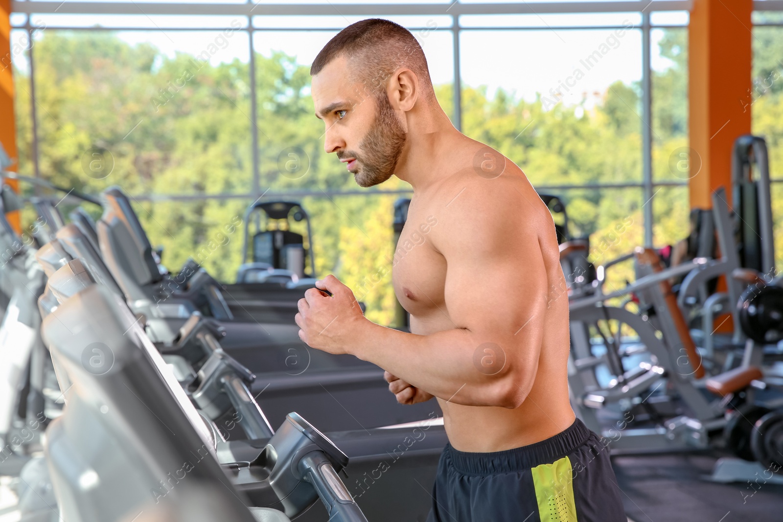 Photo of Strong young man on treadmill in gym