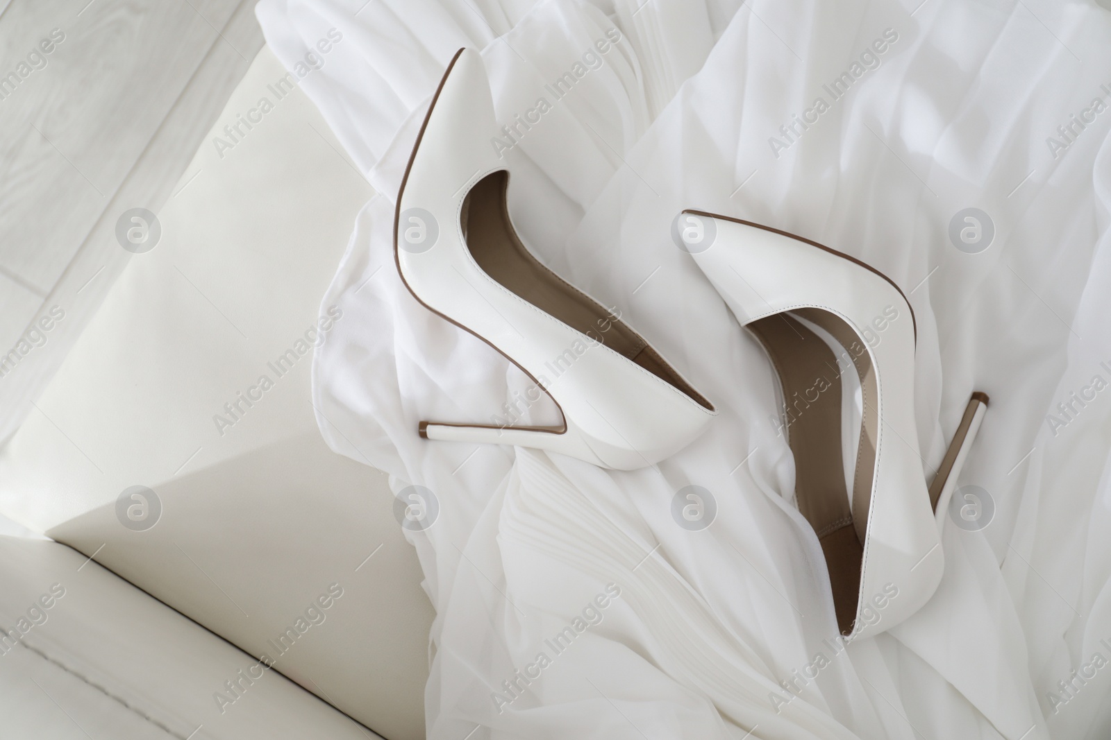 Photo of White wedding shoes on sofa, above view
