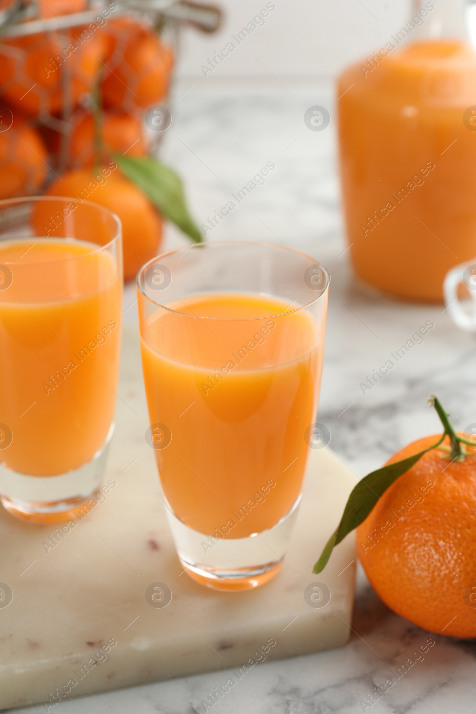 Photo of Delicious tangerine liqueur and fresh fruits on white marble table, closeup