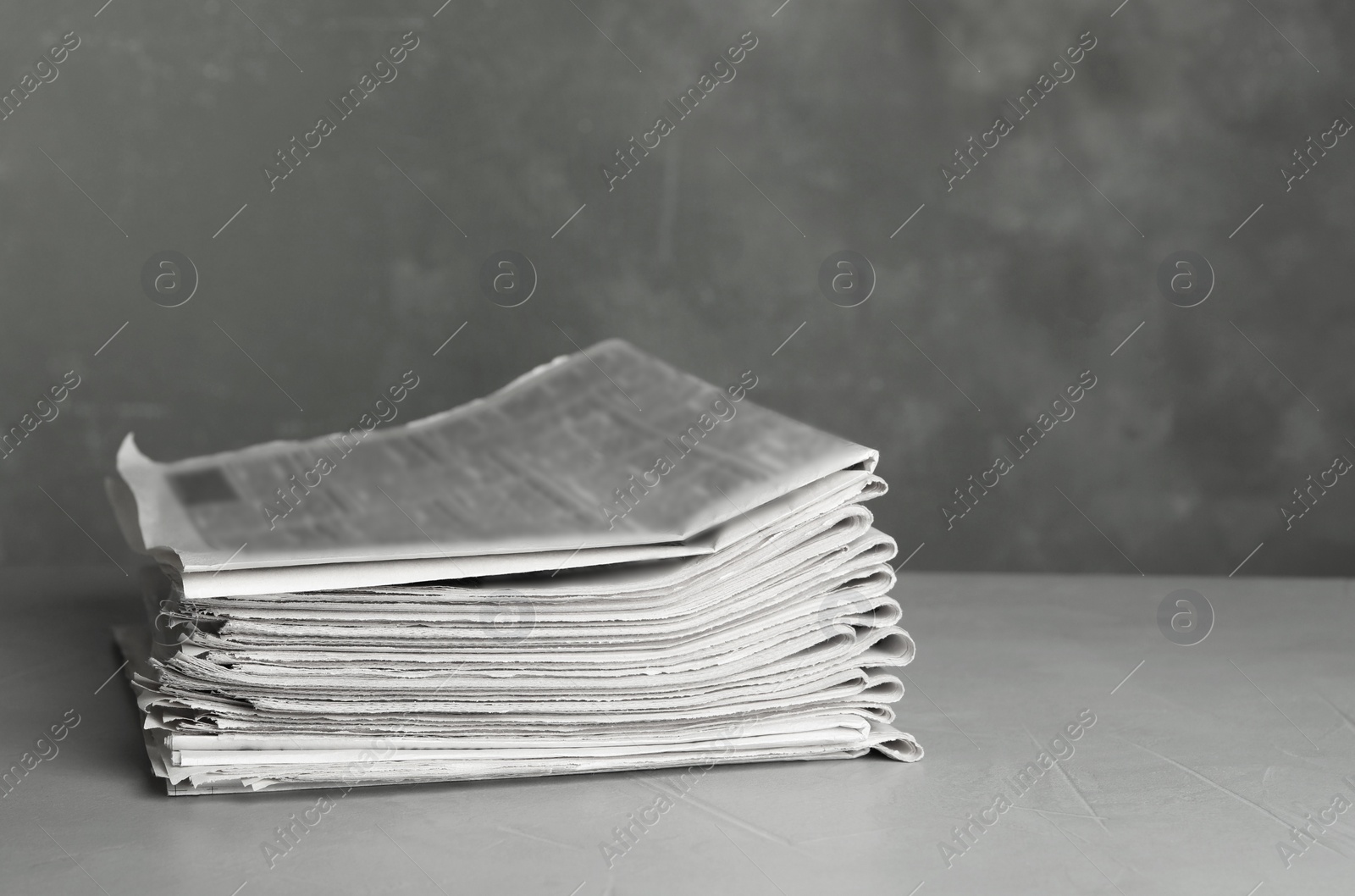 Photo of Stack of newspapers on light grey stone table. Journalist's work