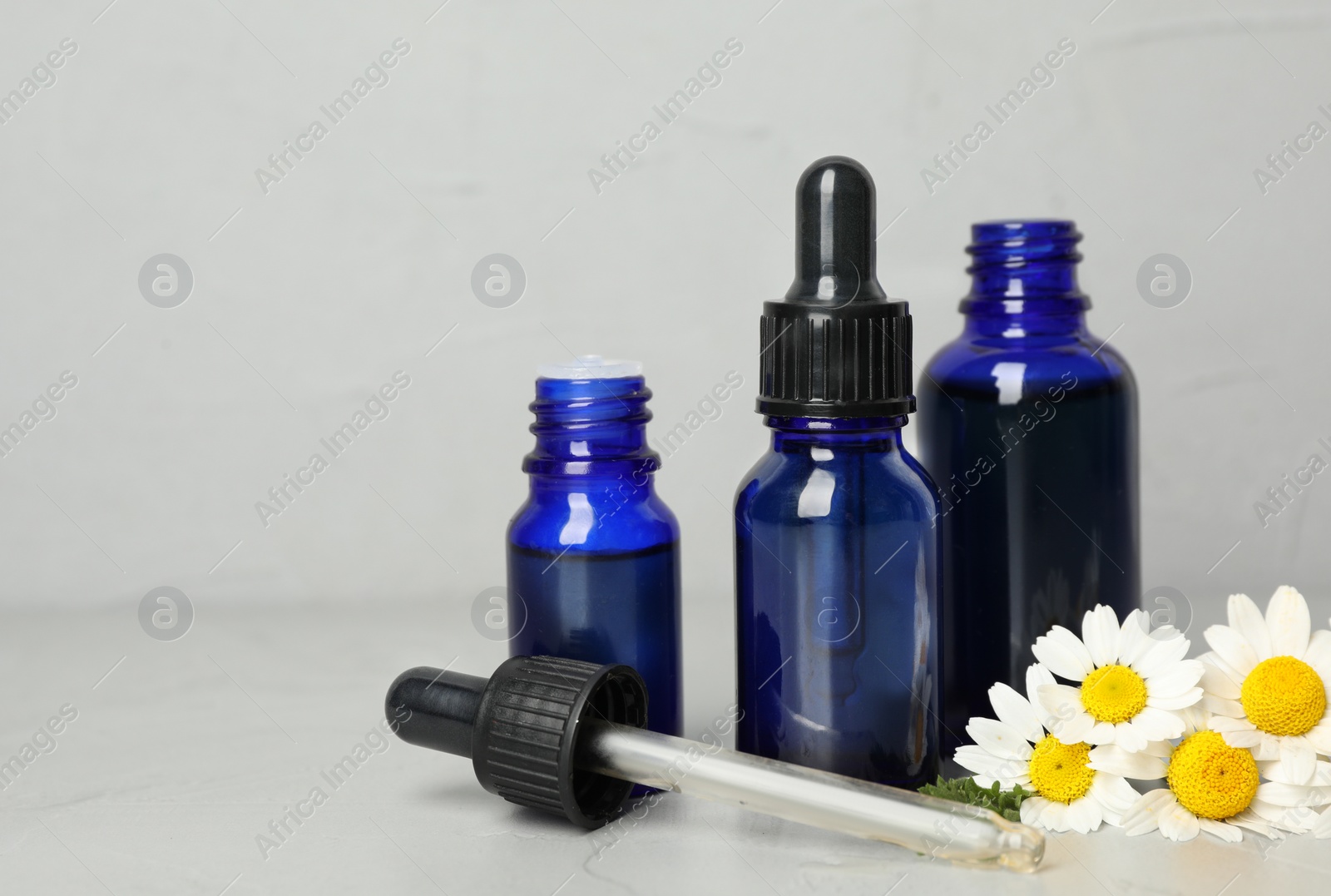 Photo of Composition with bottles of chamomile essential oil on table. Space for text