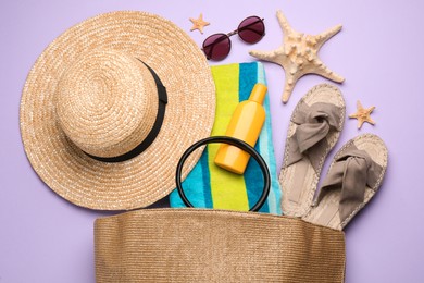 Photo of Stylish bag with beach accessories on violet background, flat lay