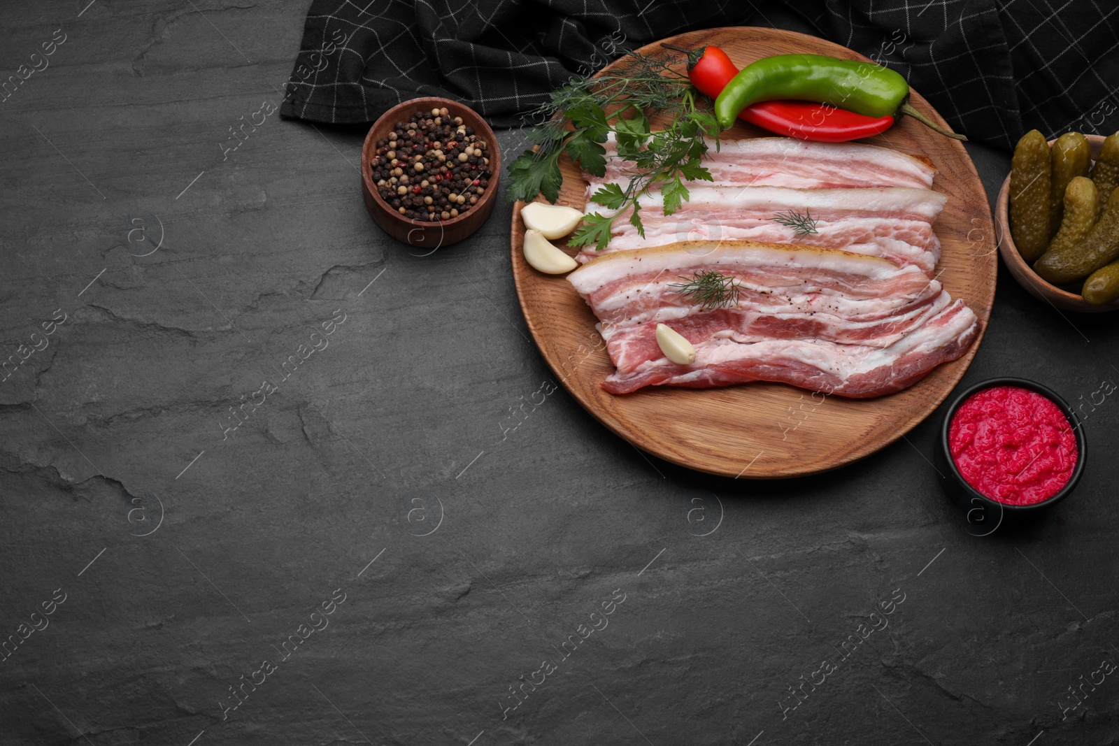 Photo of Flat lay composition with tasty pork fatback and ingredients on black table. Space for text