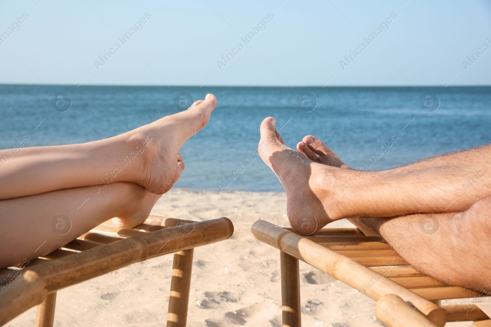 Photo of Young couple relaxing in deck chairs on beach near sea, closeup