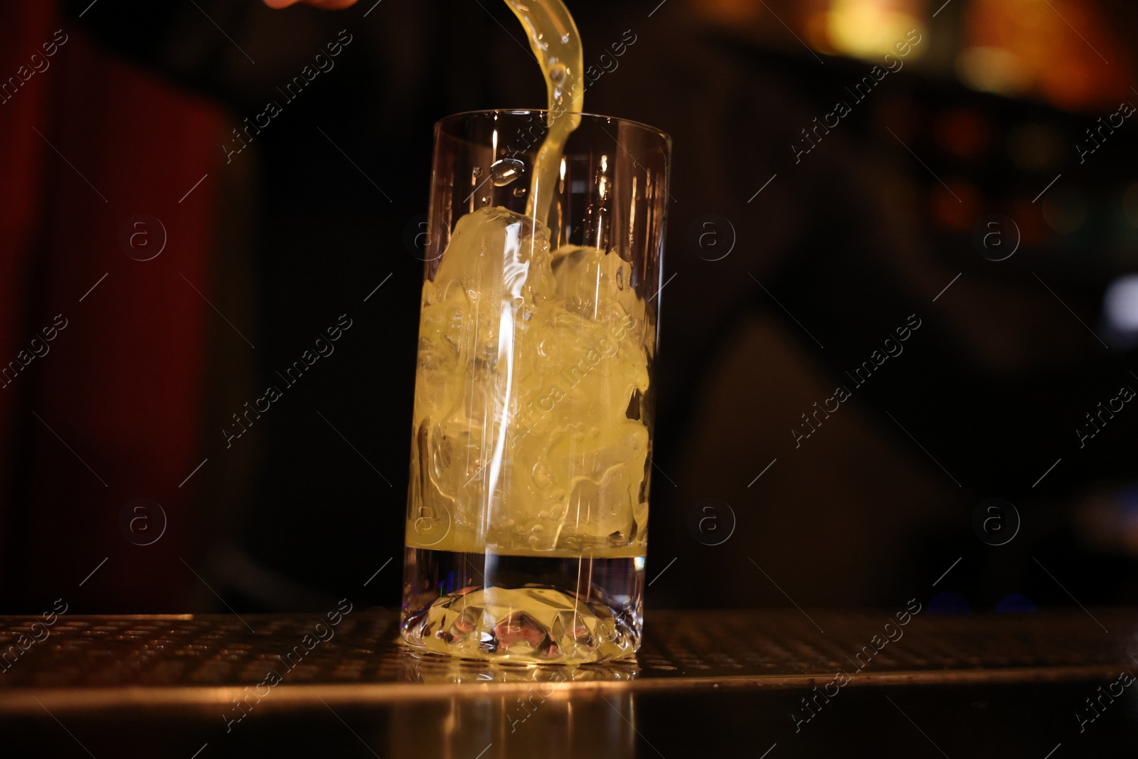 Photo of Bartender pouring energy drink into glass at counter in bar, selective focus