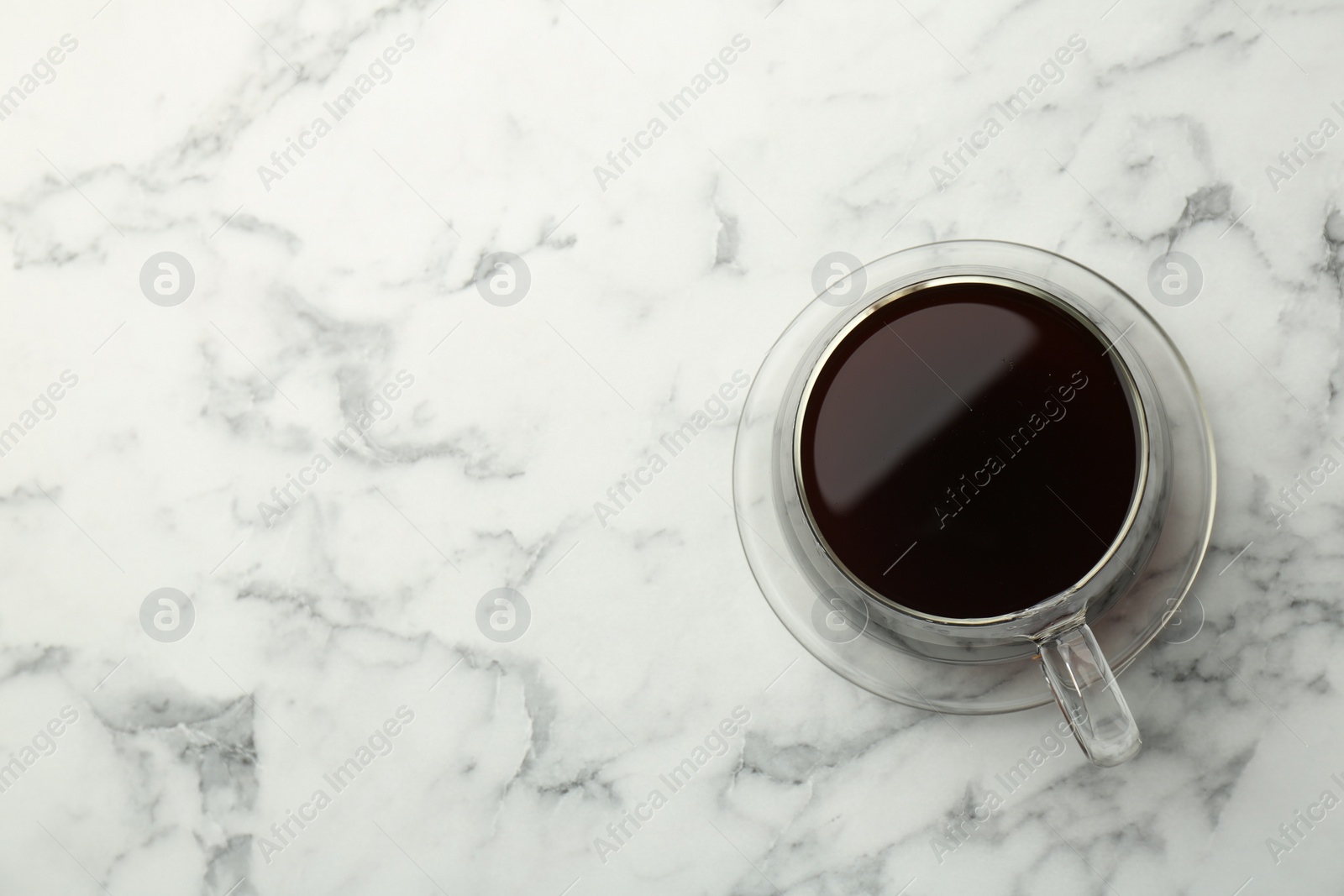 Photo of Hot coffee in cup on white marble table, top view. Space for text