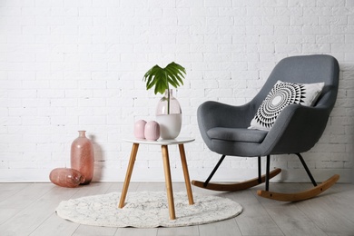 Photo of Living room interior with vases on coffee table and comfortable armchair near white wall