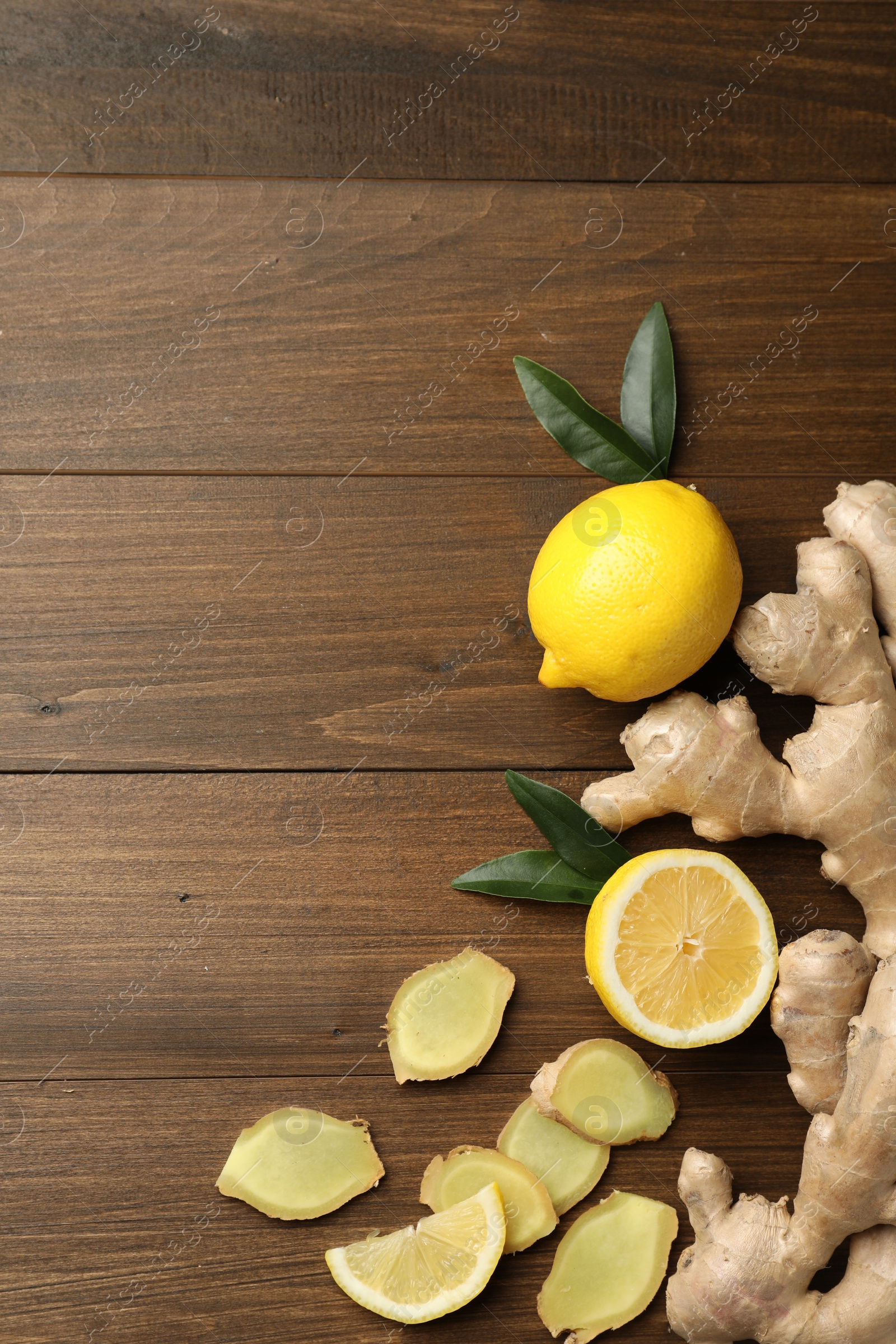 Photo of Fresh lemons and ginger on wooden table, flat lay. Space for text