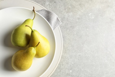 Photo of Plate with ripe pears on light background, top view. Space for text