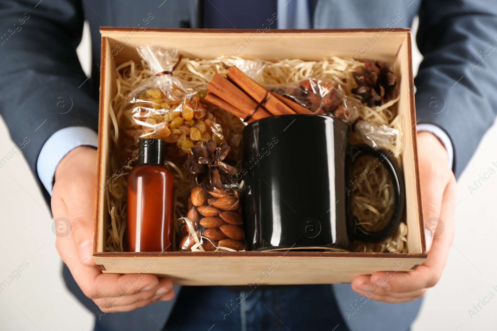 Photo of Man holding box with stylish craft gift set on light grey background, closeup