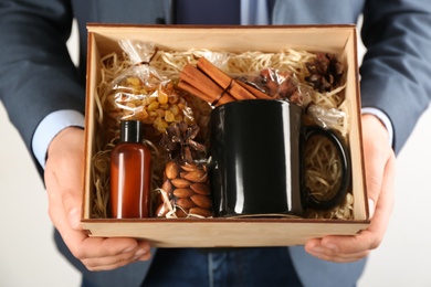 Man holding box with stylish craft gift set on light grey background, closeup