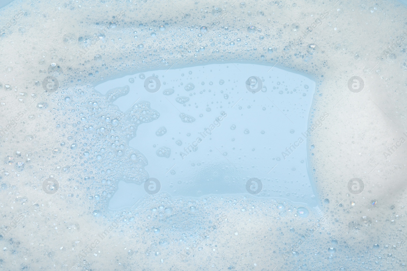 Photo of White washing foam on light blue background, top view