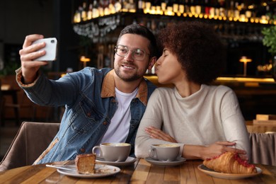 International dating. Happy couple taking selfie in cafe