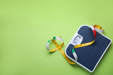 Scales and measuring tape on green background, flat lay. Space for text