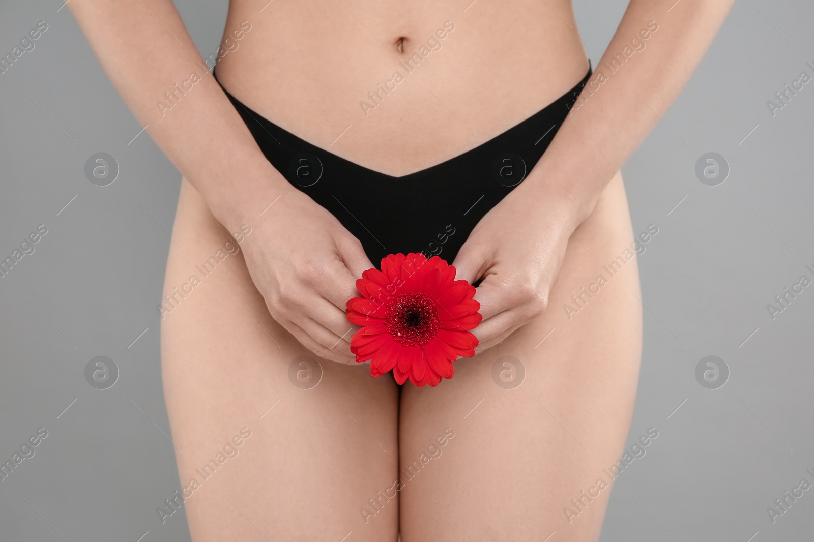 Photo of Gynecology. Woman in underwear with gerbera flower on grey background, closeup