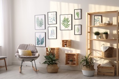 Beautiful paintings of tropical leaves on white wall in living room interior