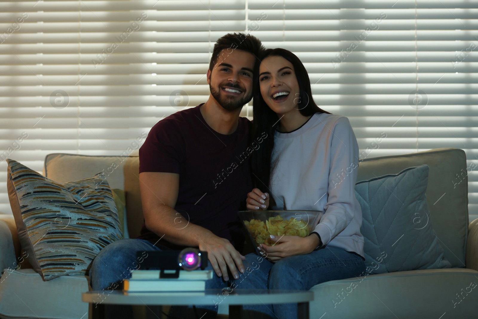 Photo of Young couple watching movie using video projector at home