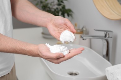 Photo of Man holding shaving foam in bathroom, closeup