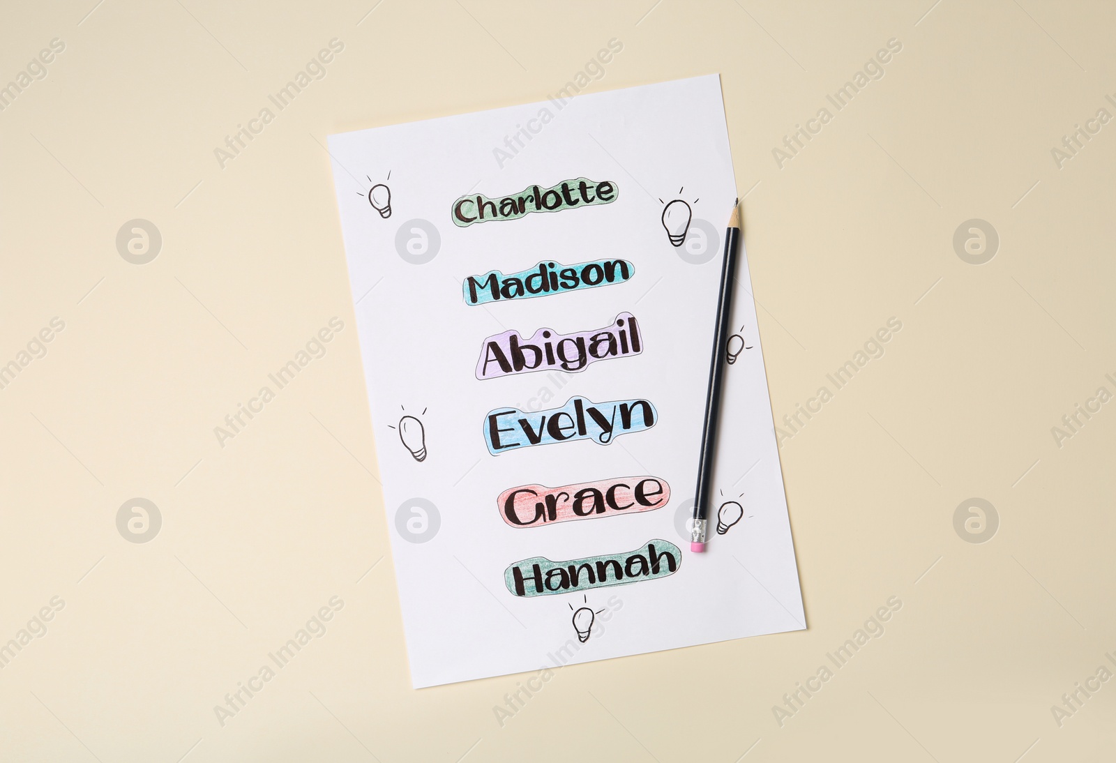 Photo of List of different baby names and pencil on beige background, top view