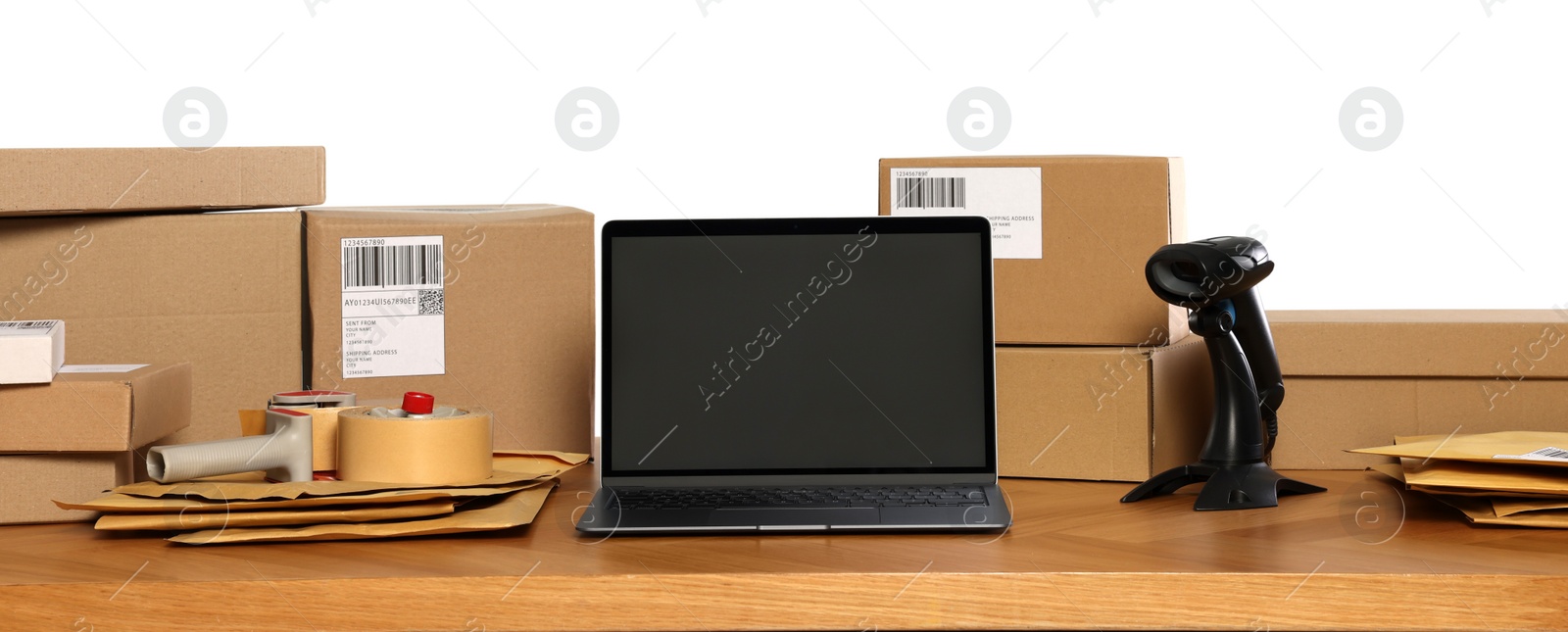 Photo of Parcels, laptop and barcode scanner on wooden table against white background. Online store